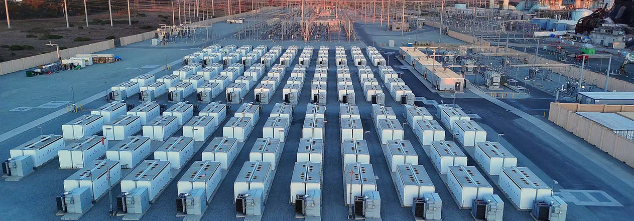 Battery storage containers next to a high-voltage substation at dusk