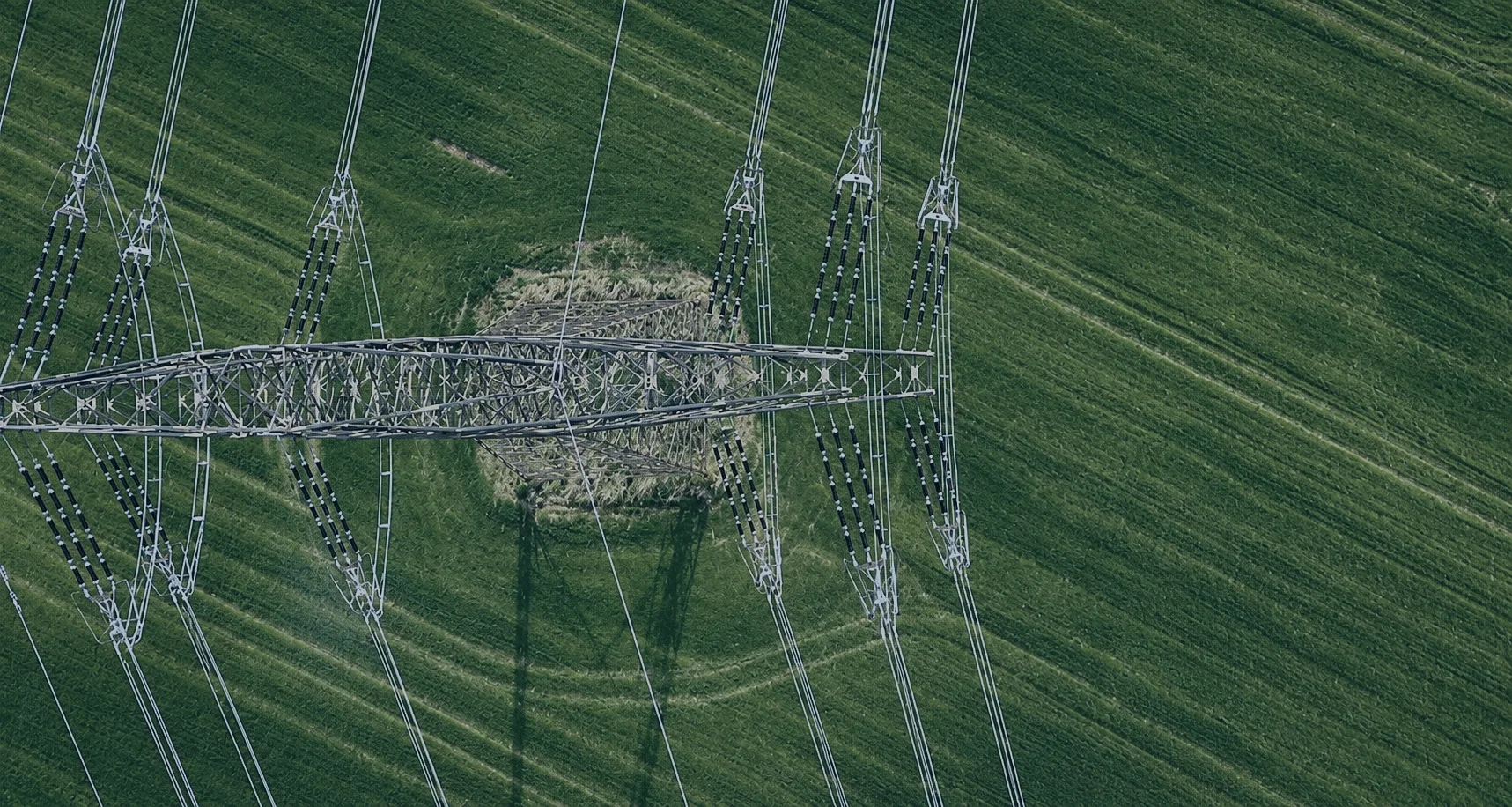 Aerial view of high-voltage transmission lines crossing green farmland